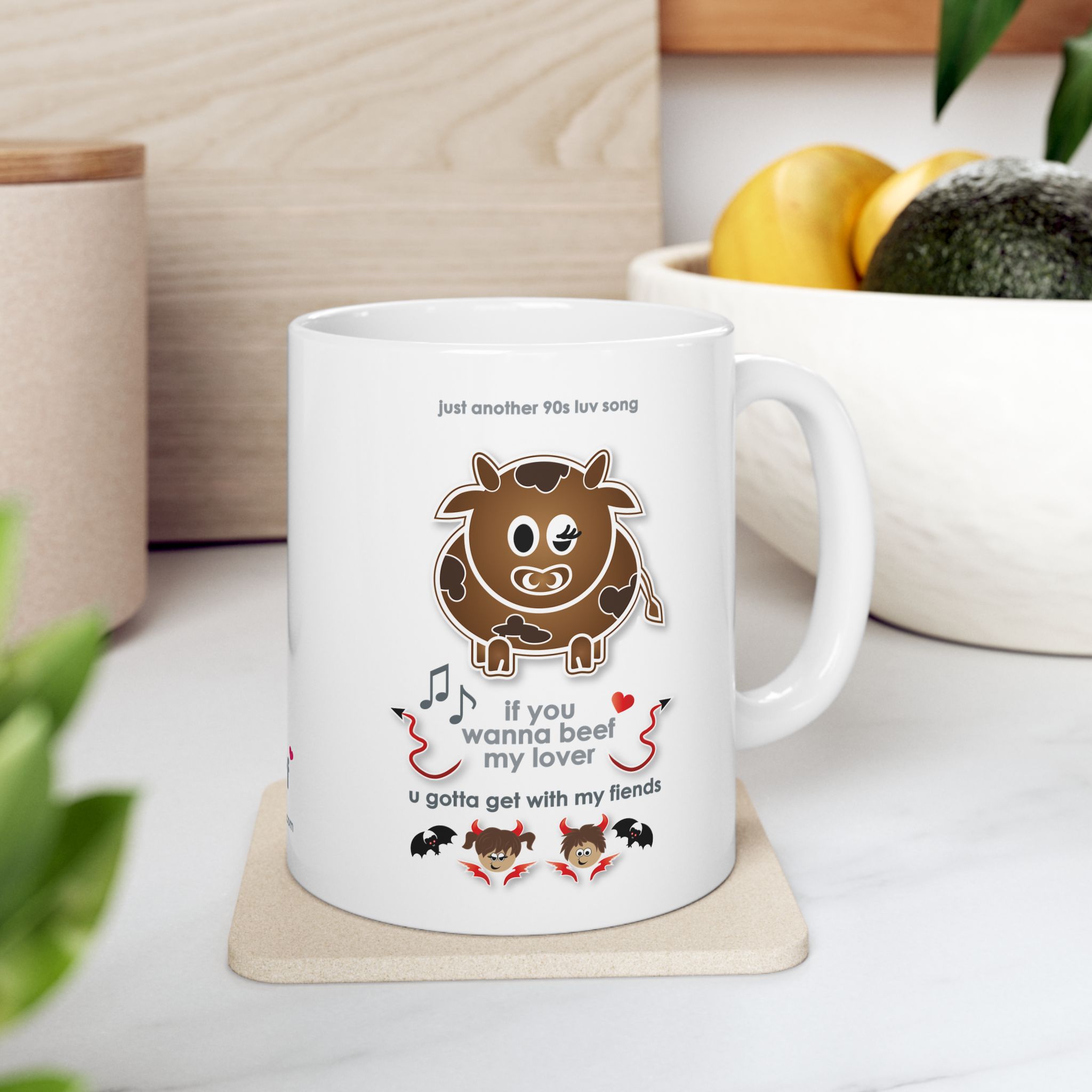 Beef My Lover Love Song Mug (11oz, 15oz) 6 White ceramic Beef my Lover love song mug featuring a cartoon cow, an angel and a fiend, text reads "if you wanna beef my lover, u gotta get with my fiends" in kitchen with fruit bowl