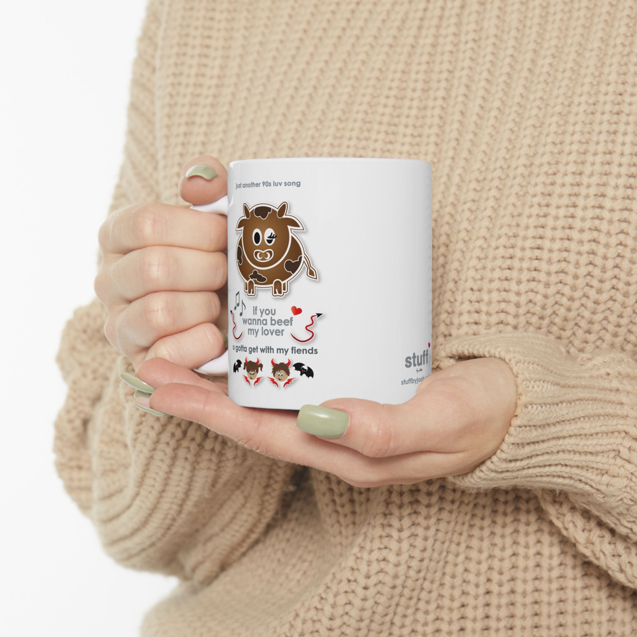 Beef My Lover Love Song Mug (11oz, 15oz) 8 White ceramic Beef my Lover love song mug featuring a cartoon cow, an angel and a fiend, text reads "if you wanna beef my lover, u gotta get with my fiends" held by woman in camel-coloured jersey